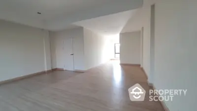 Spacious and well-lit empty living room with hardwood flooring and ample wall space, ideal for custom interior design.