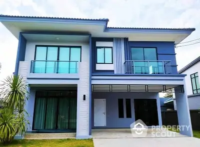 Modern two-story blue house with large windows and balcony