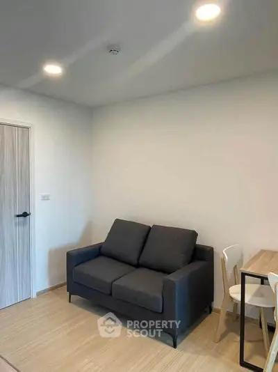Modern living room with cozy dark sofa and dining table in minimalist apartment.