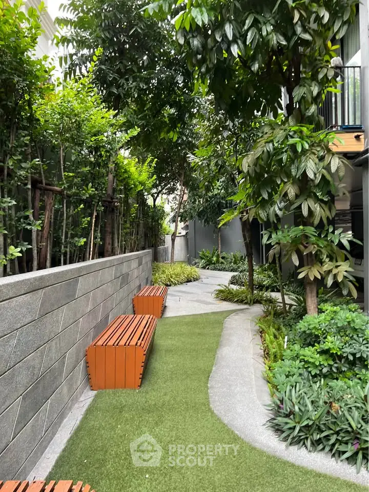 Lush garden pathway with benches in modern residential complex