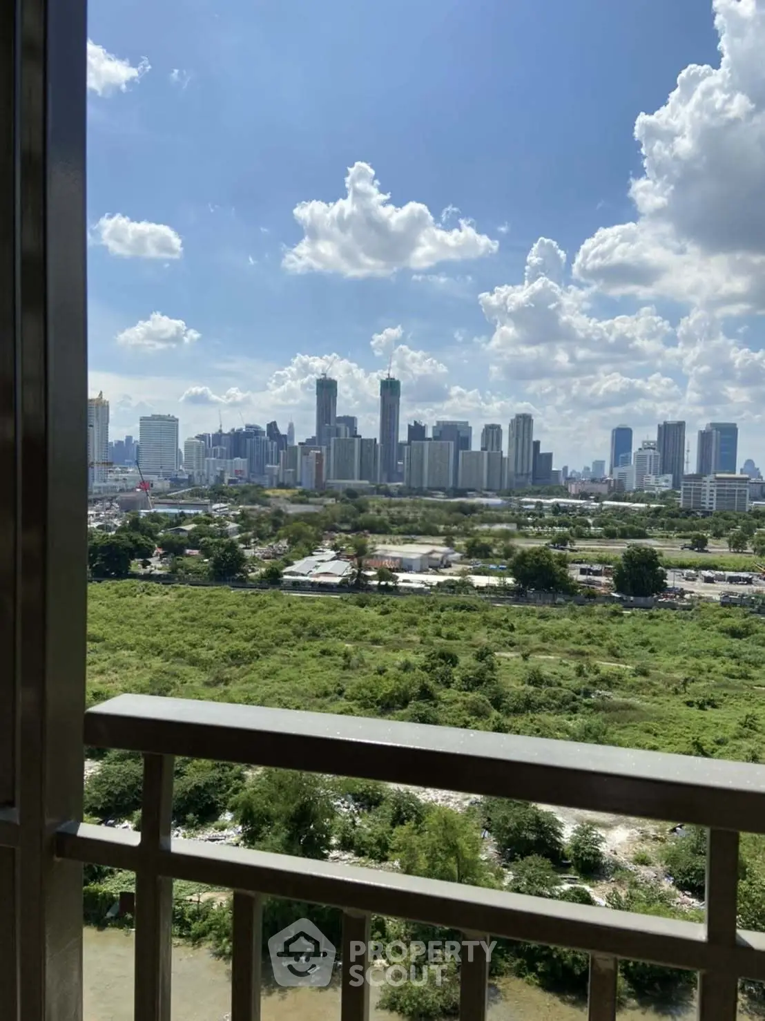 Stunning cityscape view from a balcony overlooking lush greenery and urban skyline.