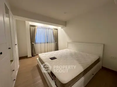 Spacious bedroom with large window and modern white furniture, perfect for relaxation.