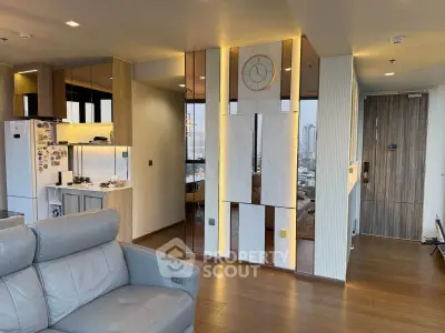 Modern living room with stylish decor and city view, featuring leather sofa and sleek kitchen area.
