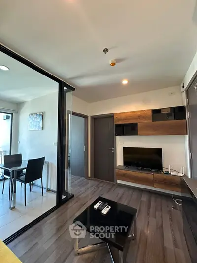 Modern living room with sleek furniture and open dining area, featuring stylish wood accents and natural lighting.