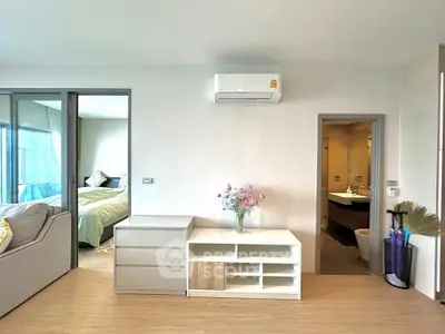 Modern apartment interior with living room, bedroom, and bathroom view, featuring sleek furniture and air conditioning.