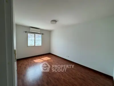 Spacious empty room with wooden flooring and natural light, perfect for customization.