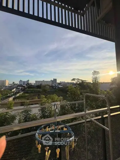 Stunning balcony view with lush greenery and cityscape at sunset, perfect for relaxation.