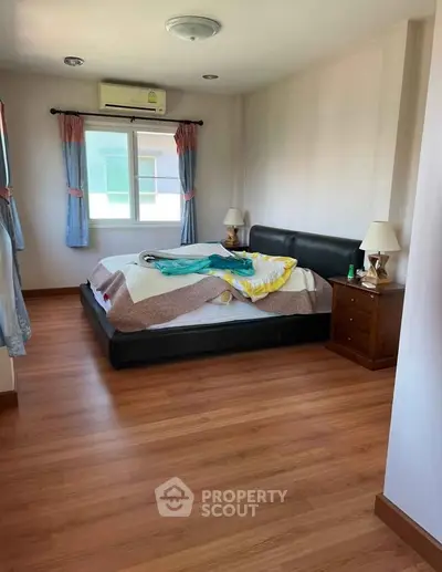 Cozy bedroom with wooden flooring and natural light, featuring a comfortable bed and bedside tables.