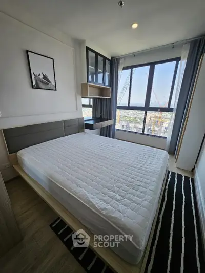 Modern bedroom with large window and city view, featuring stylish decor and natural light.