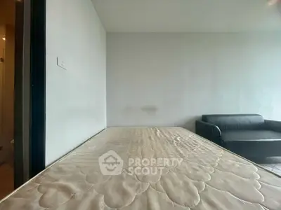 Minimalist bedroom with a mattress and modern sofa, perfect for cozy living.