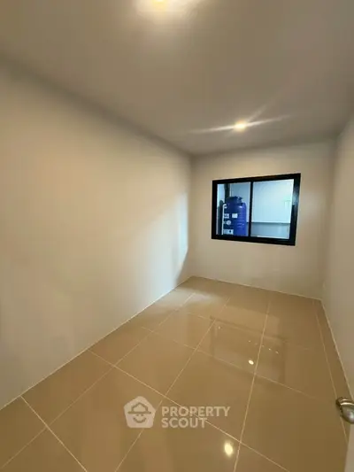 Spacious empty room with tiled floor and large window, perfect for customization.