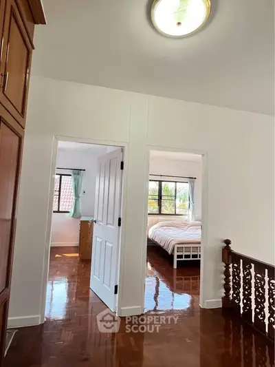 Spacious upper floor hallway leading to bright bedrooms with polished wooden floors.