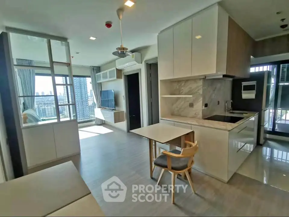 Modern open-layout living room with kitchen and city view balcony in a high-rise apartment.