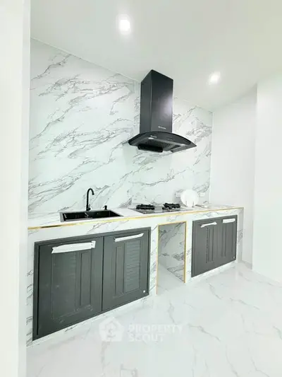 Modern kitchen with marble backsplash and sleek black appliances in a stylish open layout.