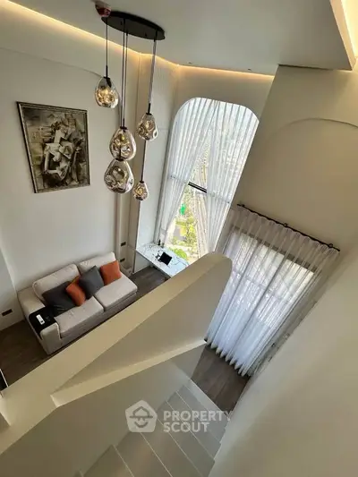 Stunning modern living room with high ceilings and elegant decor, featuring large windows and stylish lighting.