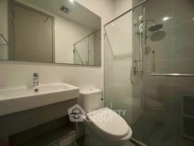 Modern bathroom with sleek fixtures and glass shower enclosure in a contemporary apartment.