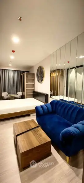 Modern living room with blue sofa and mirrored wall in stylish apartment