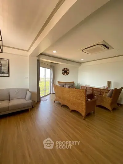 Spacious living room with wicker furniture and large window view