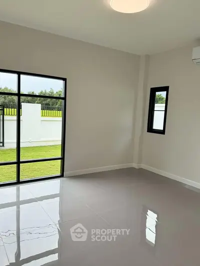 Spacious room with glossy tiled floor and large windows overlooking a green garden.