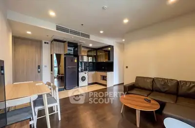Modern open-plan living room with kitchen, featuring sleek furniture and appliances.