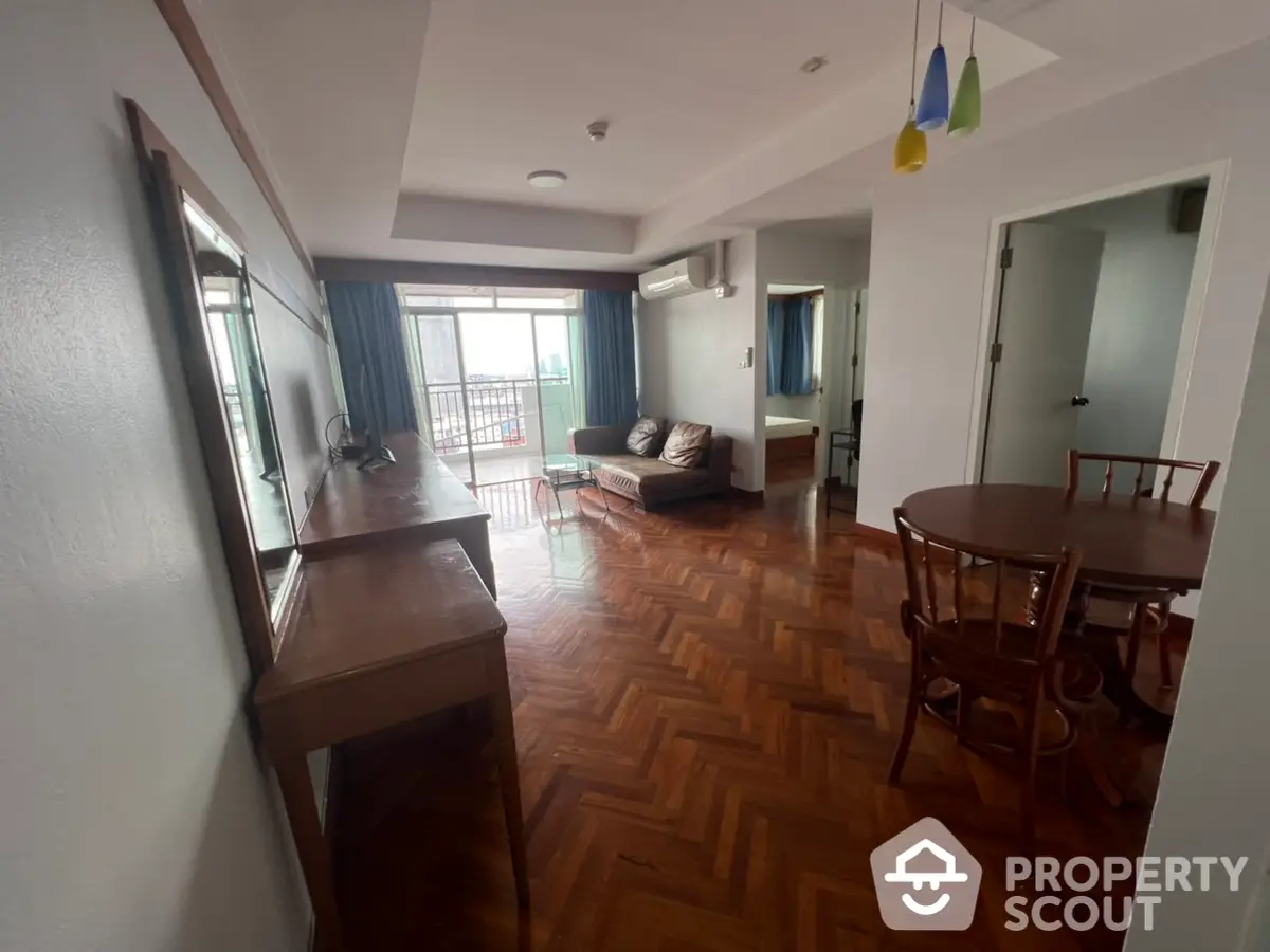 Spacious and well-lit living room with parquet flooring, leading to a cozy balcony with ample natural light, perfect for family gatherings and relaxation.