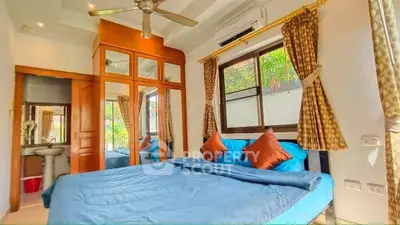 Spacious bedroom with large window, mirrored wardrobe, and cozy blue bedding, perfect for relaxation.