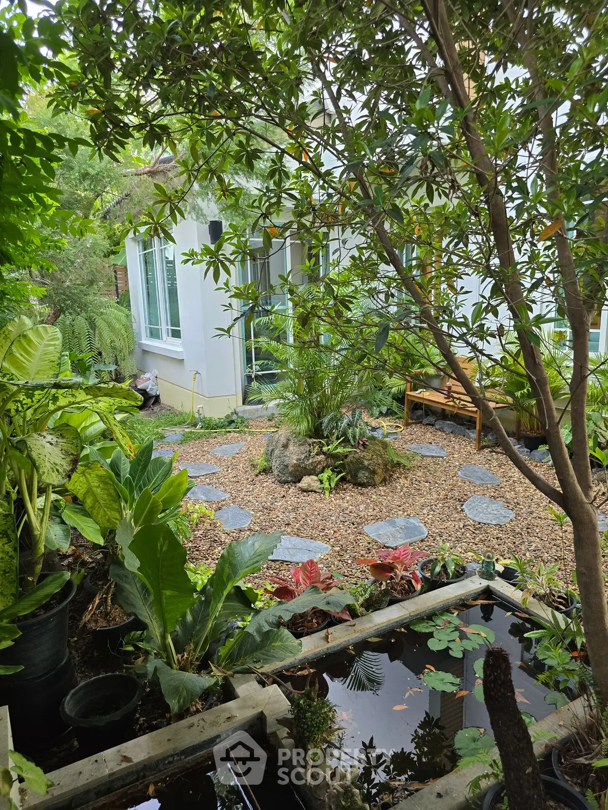 Charming garden view with lush greenery and stepping stones leading to a cozy home.