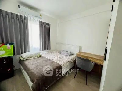 Cozy bedroom with natural light, featuring a bed and study desk, ideal for restful living.