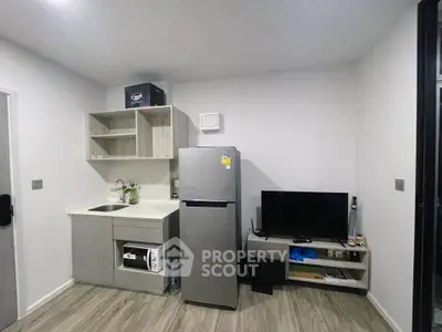Modern compact kitchen with fridge and TV in a cozy apartment