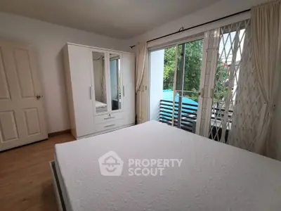 Bright bedroom with large window and wardrobe, offering a serene garden view.