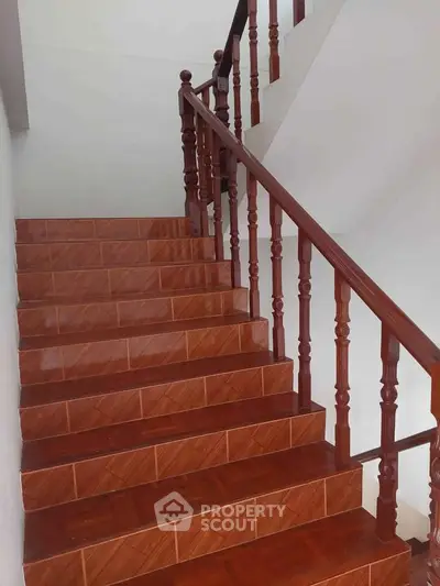 Elegant wooden staircase with polished handrails and tiled steps in a modern home.