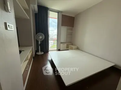 Spacious bedroom with large window and modern furnishings in urban apartment