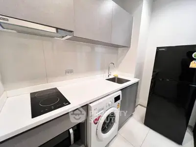 Modern kitchen with sleek appliances and compact design, featuring a washing machine and electric stove.