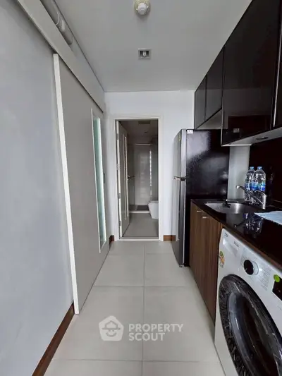 Modern kitchen with sleek appliances and washing machine in compact layout.