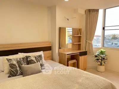 Cozy bedroom with stylish decor and large window offering natural light and scenic views.