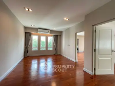 Spacious empty room with wooden floors and large windows