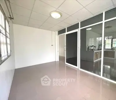 Spacious room with tiled flooring and glass partition, ideal for versatile use.