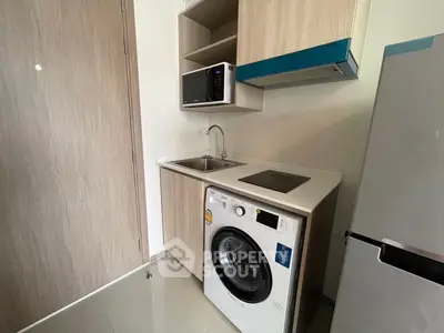 Modern compact kitchen with washing machine and microwave in sleek apartment.