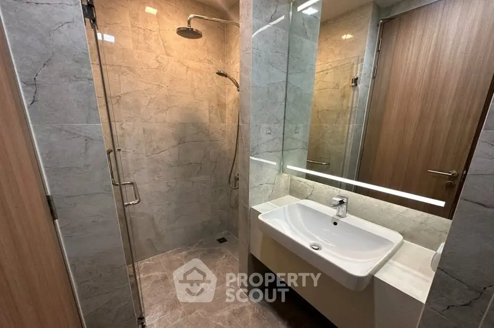 Modern bathroom with sleek design, featuring a glass shower enclosure and stylish sink.