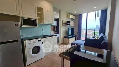 Modern open-plan living room with kitchen, featuring washing machine and city view balcony.