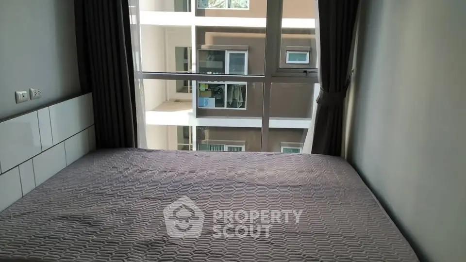 Cozy bedroom with large window offering a view of the neighboring building, perfect for urban living.