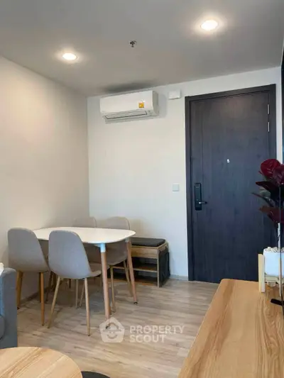 Modern apartment interior with dining area and air conditioning, featuring sleek furniture and wooden flooring.