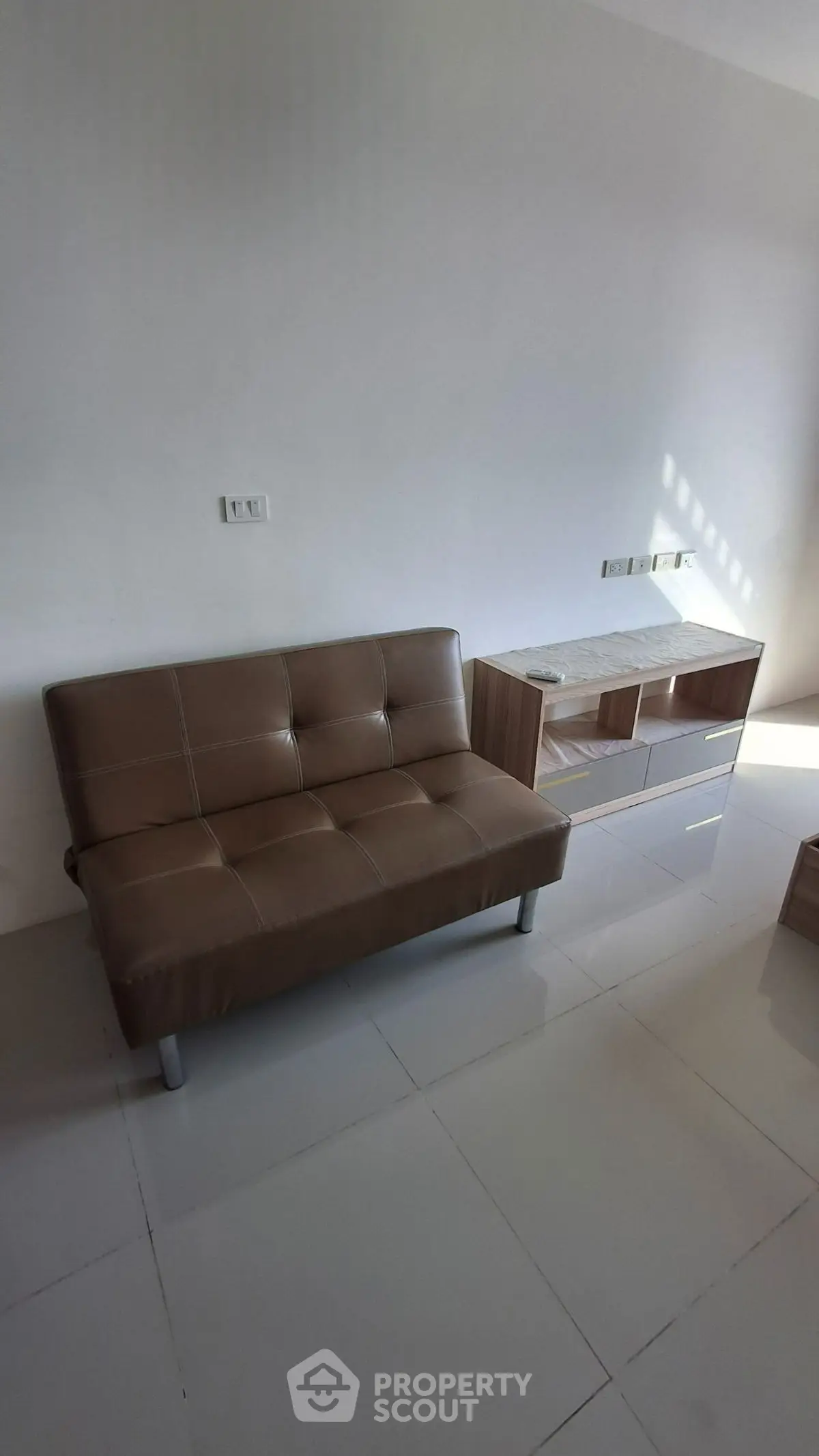 Modern minimalist living room with sleek brown sofa and stylish TV stand.