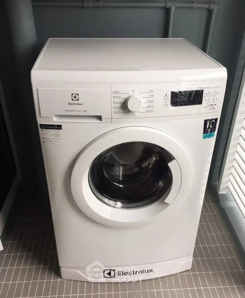 Modern Electrolux washing machine in sleek laundry area with tiled flooring.