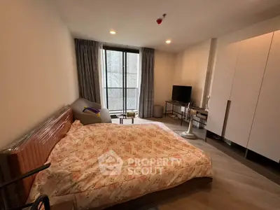 Cozy bedroom with large window and modern furnishings in a stylish apartment.