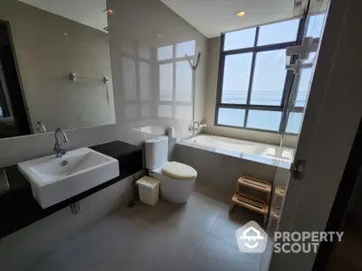 Luxurious bathroom with ocean view, featuring modern fixtures and a spacious bathtub.