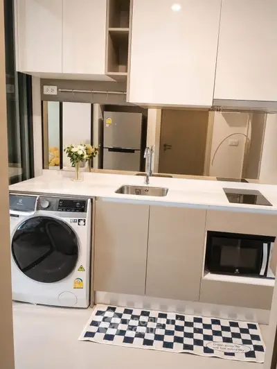 Modern kitchen with sleek appliances and washer, featuring a stylish open layout and elegant cabinetry.