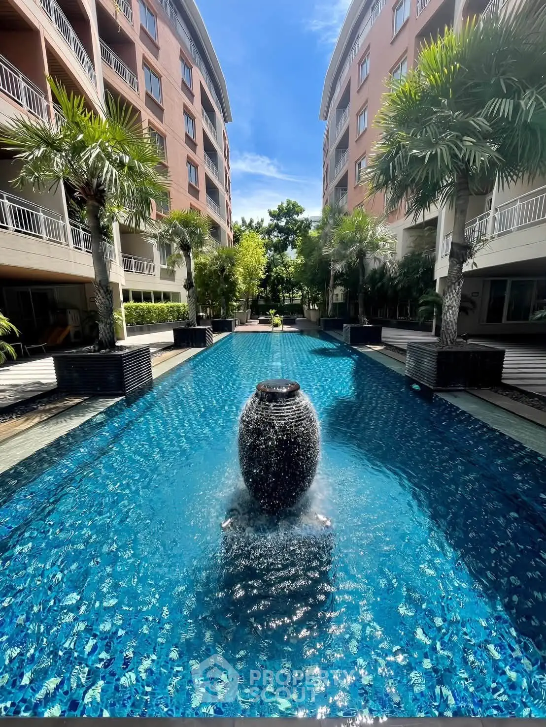 Luxurious apartment complex with stunning pool and lush greenery, perfect for modern living.