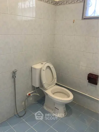 Spacious bathroom with modern toilet and tiled walls, ideal for comfortable living.
