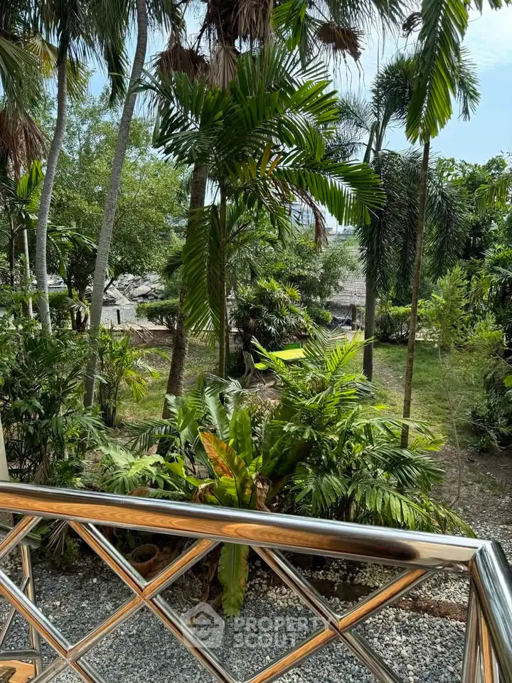 Tropical garden view from a balcony with lush greenery and palm trees.